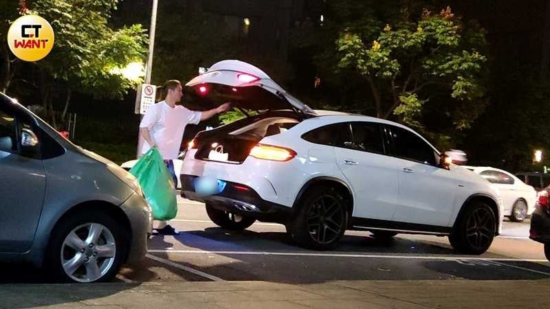 熊熊的老公忙著將汽車後車廂內的數袋衣服搬進店內。(圖/本刊攝影組)