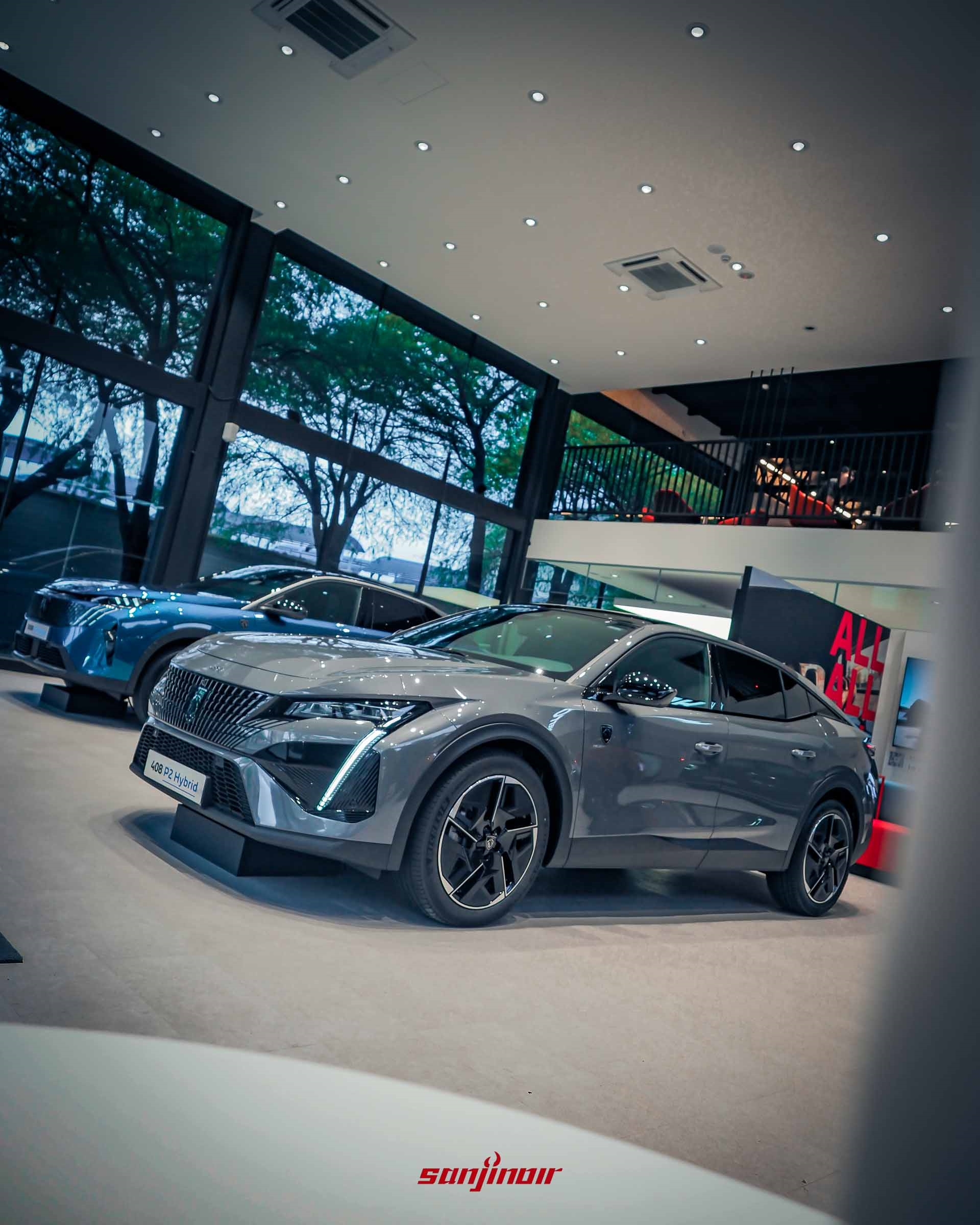 一輛灰色 PEUGEOT 408 P2 Hybrid 的對角線視角。車輛具有光滑的轎跑車流線型線條，大型多幅合金輪圈和垂直日行燈。