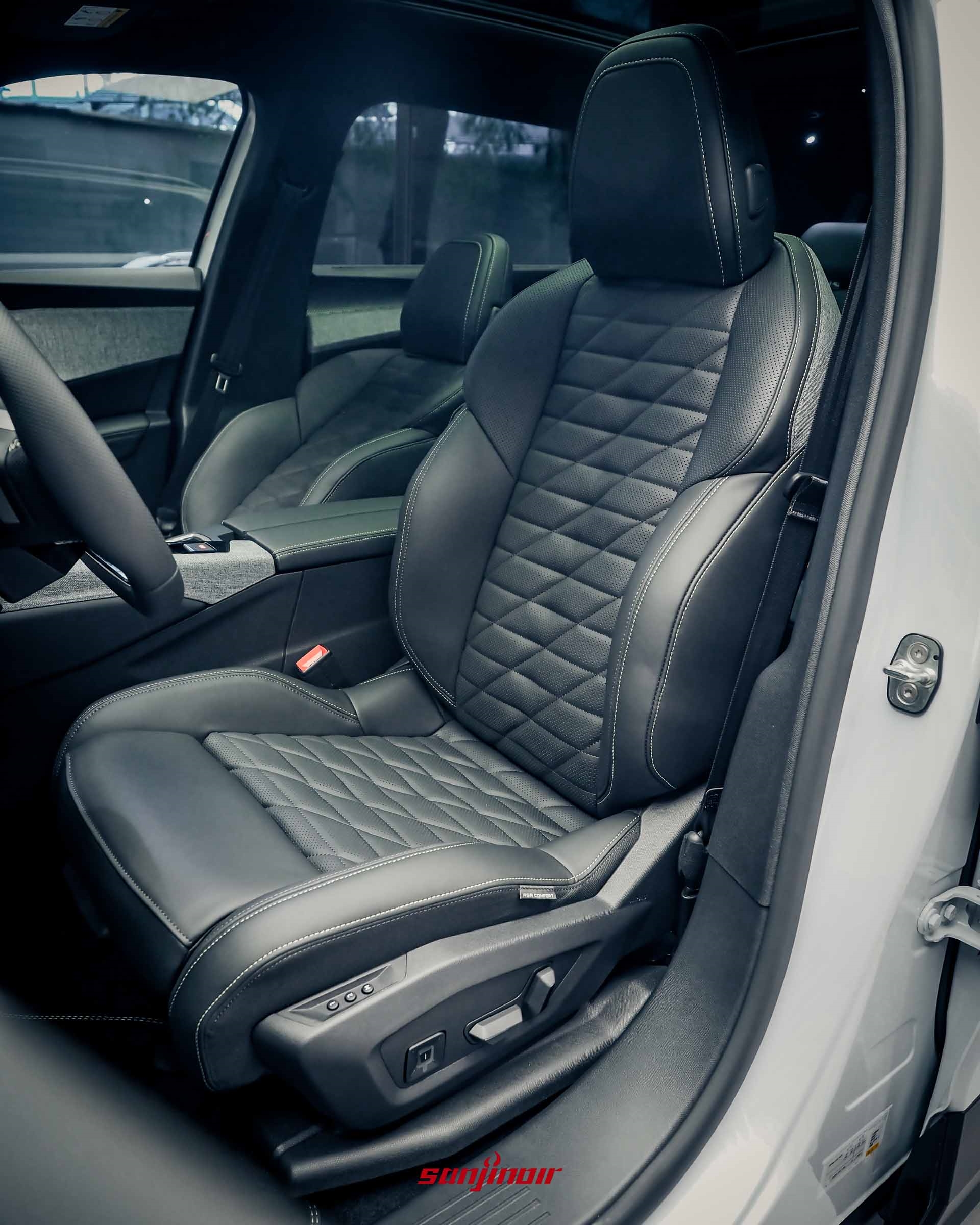 一輛白色 PEUGEOT SUV 5008的雙前座內飾特寫。座椅為黑色皮革，具有獨特的鑽石形縫線圖案，駕駛座具有多向電動調節開關。