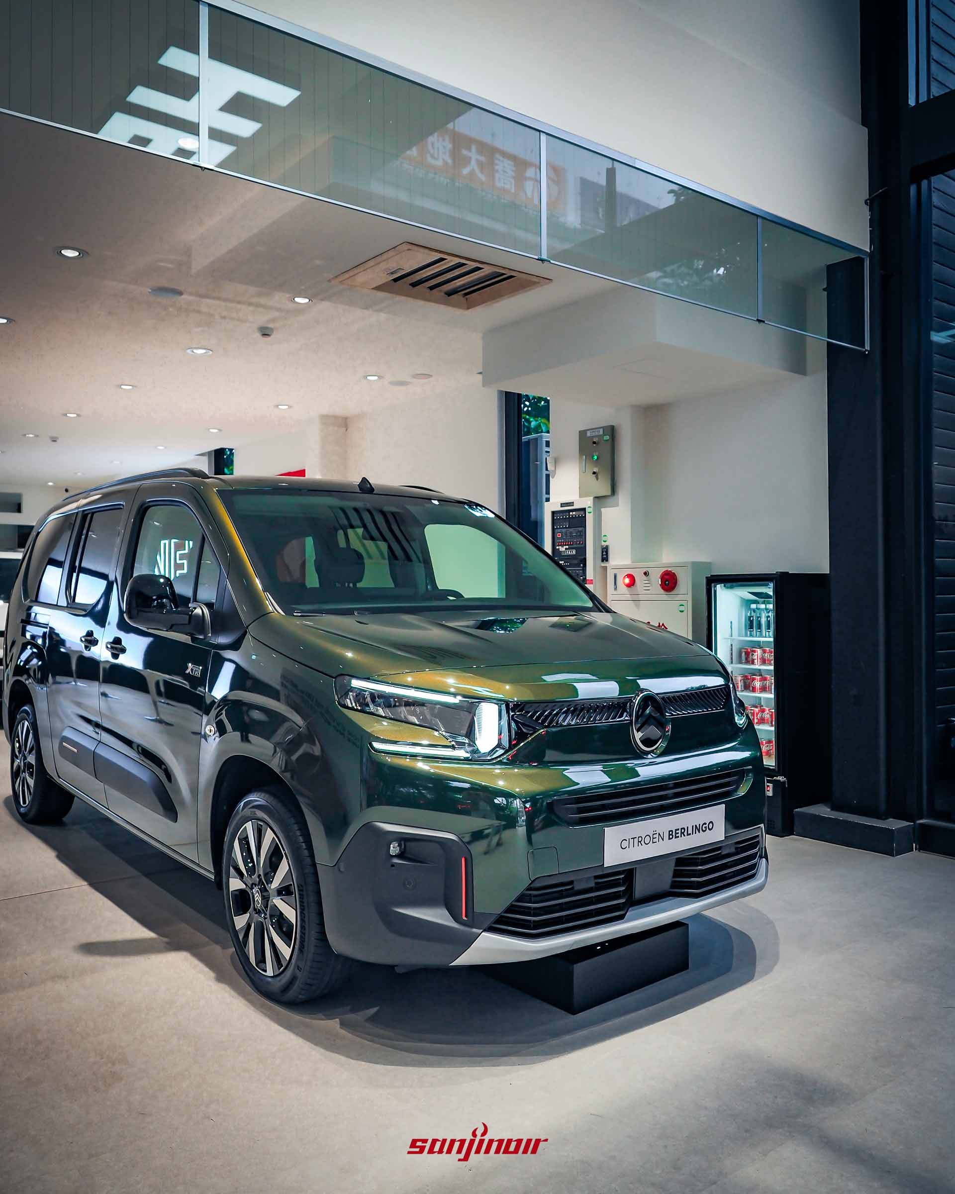 一輛深綠色 CITROËN BERLINGO MPV。車輛具有新款雪鐵龍標誌，方形大燈和垂直側面保護條。